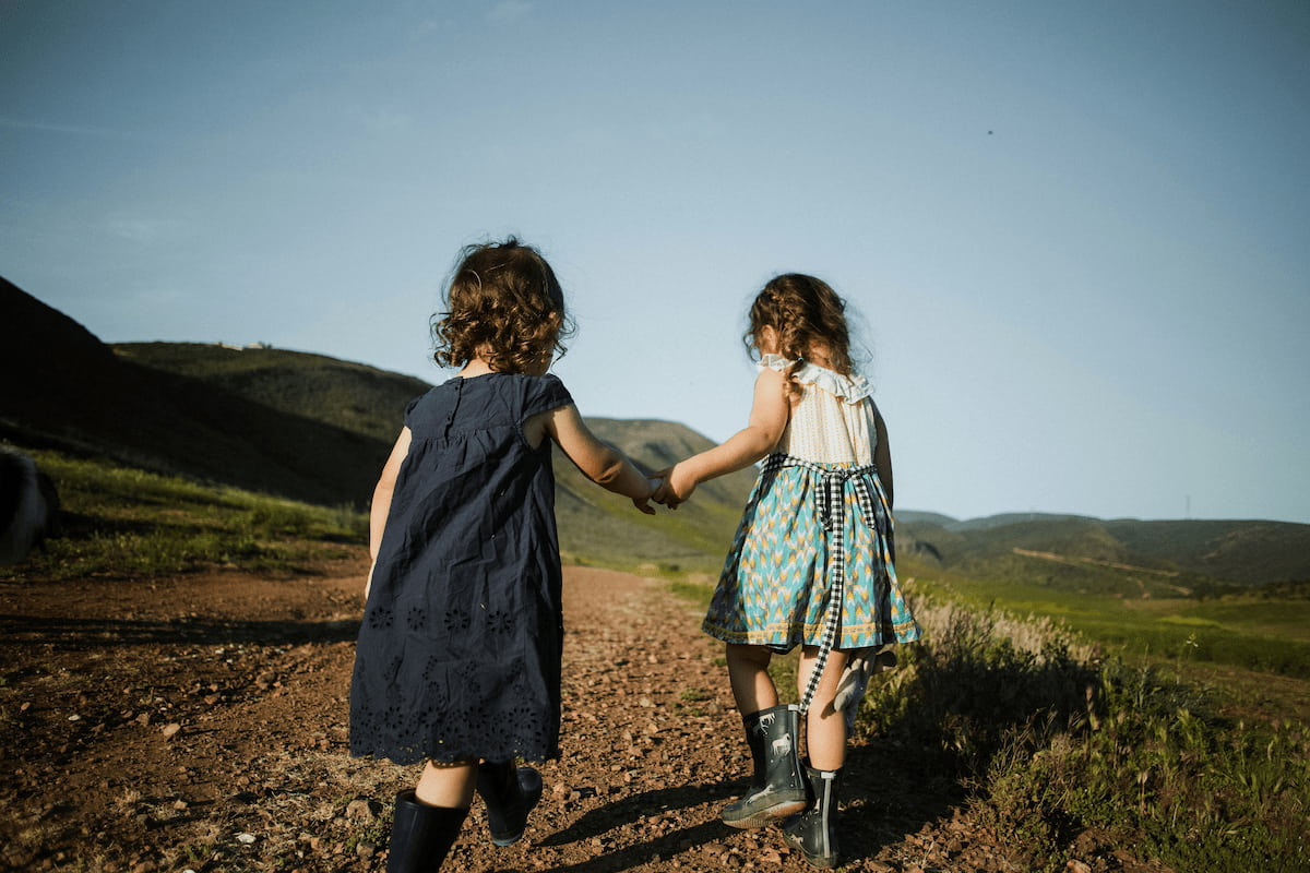 Niñas de espaldas de la mano en el campo paseando y jugando